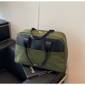 Close-up of army green canvas handbag with black leather accents and gold zipper details