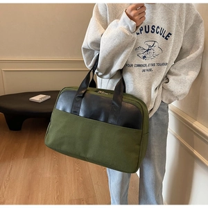 Detail of a large canvas tote bag in olive green and black being held by a model