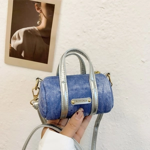 Detail of a mini denim cylinder bag with silver metallic leather trim and KOYOKA nameplate