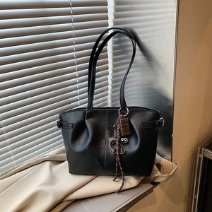 Detail of black pebbled leather tote featuring trendy pleated design and cute cat charms