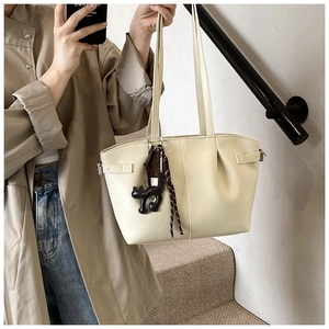 Detail of cream pleated PU leather tote bag with cute black cat charm accessory