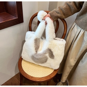 Detail of white faux fur tote bag with plush pom-poms and cute rabbit embroidery patch