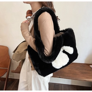 Close-up of black and white plush faux fur tote bag with soft texture and wide shoulder strap