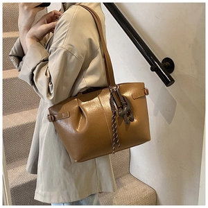 Brown leather tote bag featuring a cute cat charm and adjustable shoulder strap