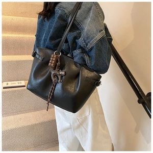 Detail of black PU tote bag featuring cute cat pendant and spacious shoulder strap design