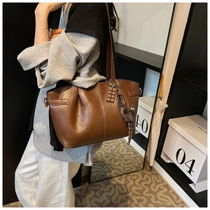 Detail of dark brown tote bag with textured PU leather and a cute cat charm pendant