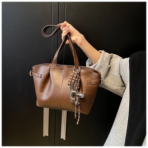 Close-up of brown PU leather tote bag featuring unique chocolate and cat shaped charms