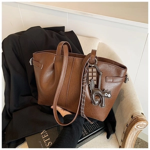 Detail of dark brown leather tote bag with unique cat and chocolate bar bag charms