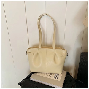 Detailed view of cream PU leather tote bag featuring pleated texture and silver buckles