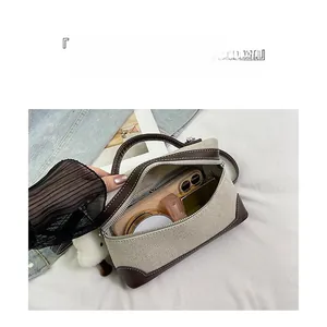 Detail of canvas and leather handbag showing interior capacity for phone and cosmetics