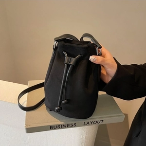 Chic black drawstring bucket bag with decorative stitching and adjustable shoulder strap