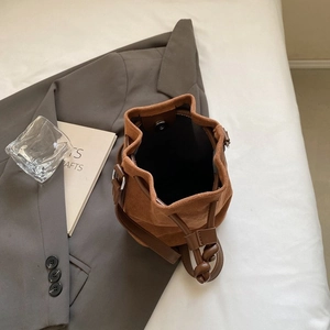 Vintage brown suede bucket bag with drawstring and magnetic closure on grey blazer