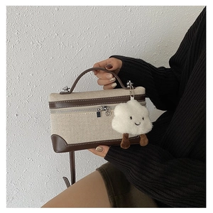 Close-up of canvas handbag with brown leather trim and cute white cloud pendant