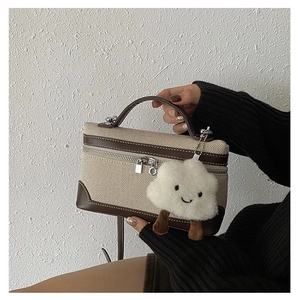 Close-up of canvas and leather patchwork handbag with a cute cloud plush charm