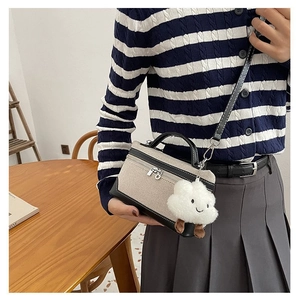 Detail of mini box bag with cream canvas, black trim and cute cloud charm on a model