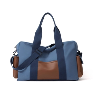 Sac de voyage en toile bleue avec poches en cuir brun et bandoulière réglable