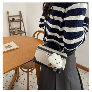 Detail of canvas and leather patchwork crossbody bag with a cute plush cloud charm