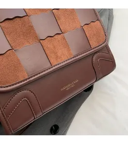 Detail of woven brown leather and suede textures with gold logo on retro backpack