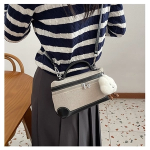 Detail of canvas crossbody bag with leather trim and plush cloud charm on a model