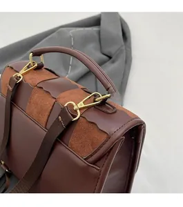 Detail of dark brown leather and suede stitching bag with gold metal hardware