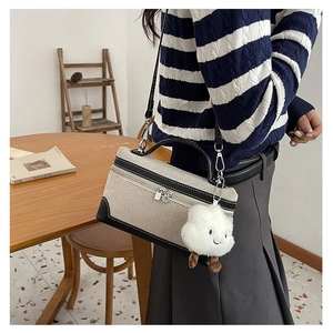 Detailed view of canvas crossbody bag with leather trim and plush cloud charm
