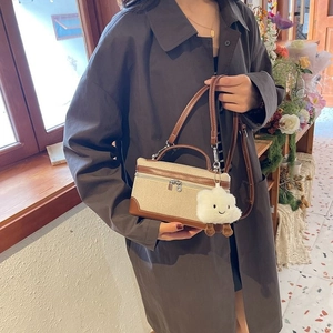 Detail view of retro canvas handbag with brown leather trim and cute plush charm