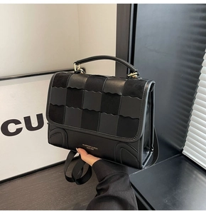 Detail of black checkerboard patchwork handbag with wavy flap and golden lettering logo
