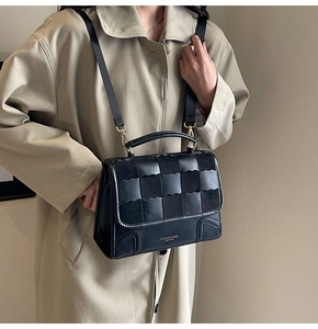 Detail of black leather handbag with checkered woven texture and gold hardware accents