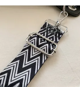 Close-up of adjustable black and white zigzag woven strap with silver metal lobster clasps