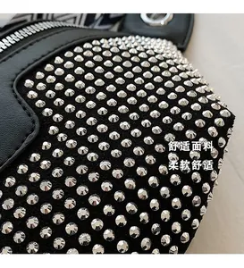 Detail of silver rivets on black suede fabric with metallic zipper and textured strap