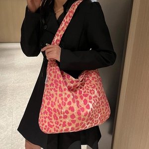 Detailaufnahme einer Canvas-Tragetasche mit rosa Leopardenmuster am Modell mit schwarzem Mantel