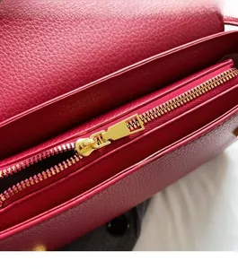 Close-up of smooth golden metal zipper and lychee leather texture on fuchsia bag