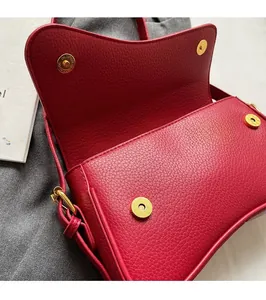 Macro detail of red lychee grain leather handbag featuring dual gold magnetic closures