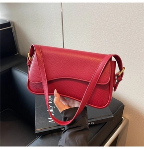 Detail of red pebbled leather shoulder bag with curved flap and gold-tone hardware