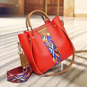 Detail of red PU leather tote with colorful woven strap and gold hardware accents