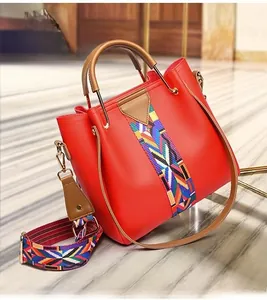 Detail of red PU tote bag featuring pebbled texture and colorful woven shoulder strap
