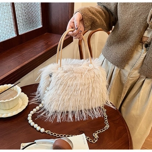 Détail du sac à main en peluche blanc cassé avec chaîne de perles et accents dorés