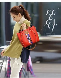 Outdoor shot of red PU leather tote with colorful woven strap and gold hardware accents