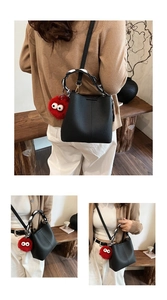 Detail of black pebbled leather bucket bag with silk scarf and red plush monster charm