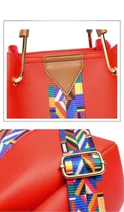 Detail of red PU tote bag featuring a colorful geometric woven strap and gold metal hardware