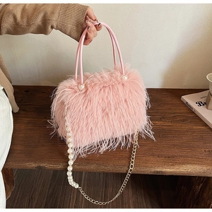 Détail d'un sac à main en peluche rose avec texture fausse fourrure et chaîne perle