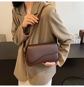 Detail of dark brown pebble leather shoulder bag with unique wavy flap and gold hardware