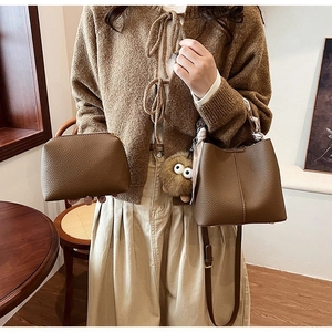 Brown lychee grain bucket bag with silk scarf handle and plush charm detail