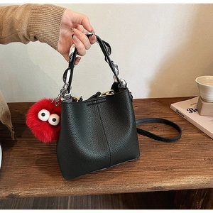 Minimalist black bucket bag with printed silk scarf handle and red monster bag charm