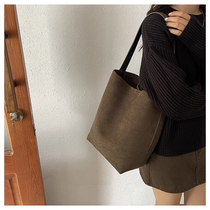 Detail view of large brown suede hobo bag shown from the side with black shoulder strap