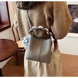 Detail of grey lychee leather bucket bag with silk scarf handle and plush eye charm
