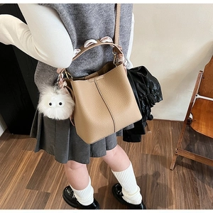 Detail of khaki bucket bag with silk scarf handle and white plush charm on a child model
