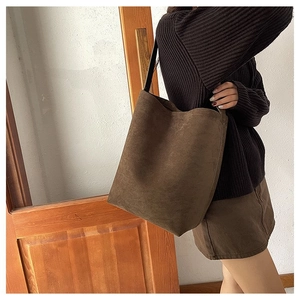 Detail of dark brown matte suede hobo bag shown with model's retro autumn outfit