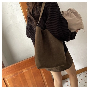 Detail of dark brown suede tote bag with beige drawstring pouch and wide shoulder strap