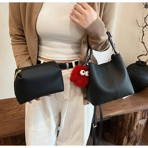 Close-up of black litchi texture shoulder bag with monster pendant and inner pouch